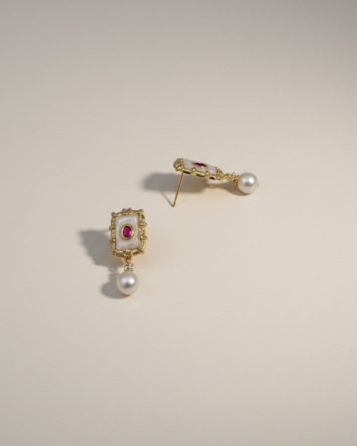 Pair of gold earrings with gemstones on a beige background