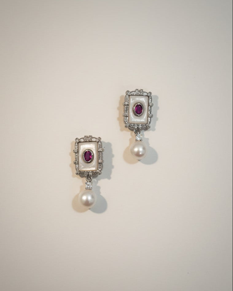 Pair of earrings with gemstones and pearls on a light gray background