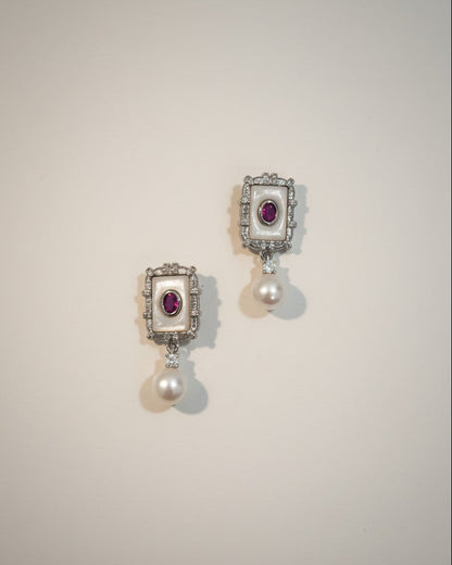 Pair of earrings with gemstones and pearls on a light gray background