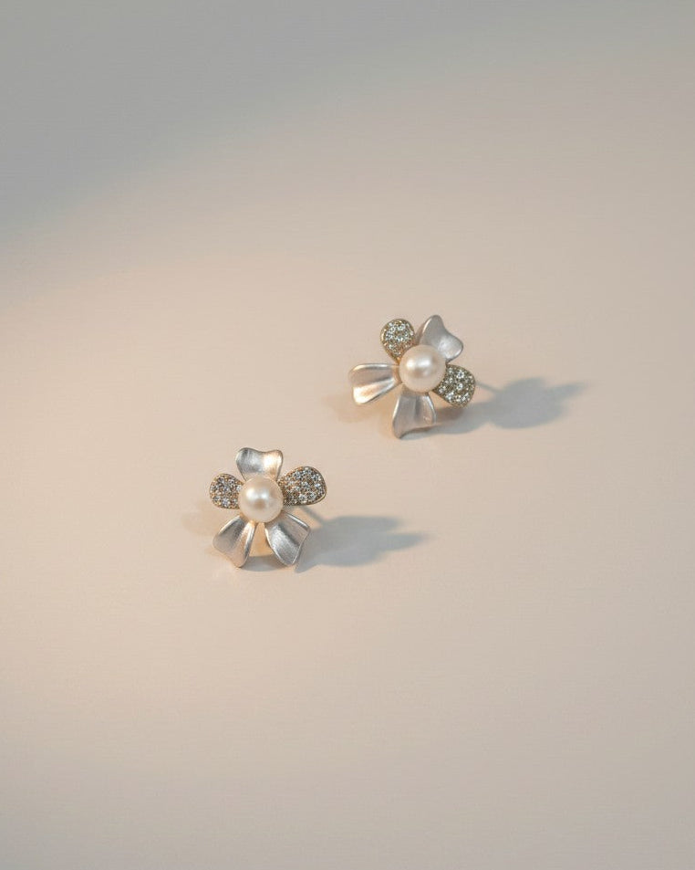 Pair of floral earrings with pearls and gemstones on a gradient background