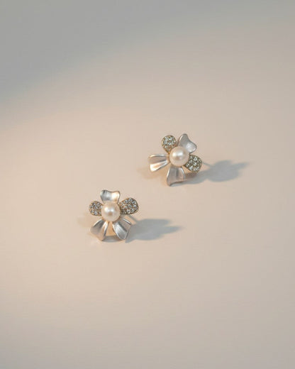 Pair of floral earrings with pearls and gemstones on a gradient background