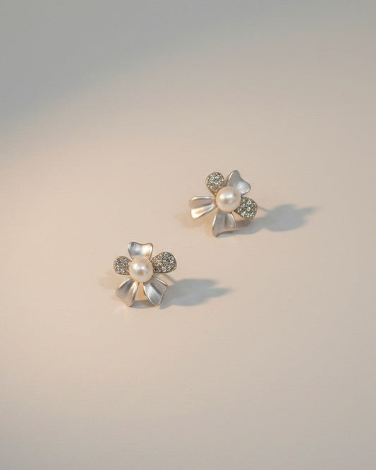 Pair of floral earrings with pearls and gemstones on a gradient background