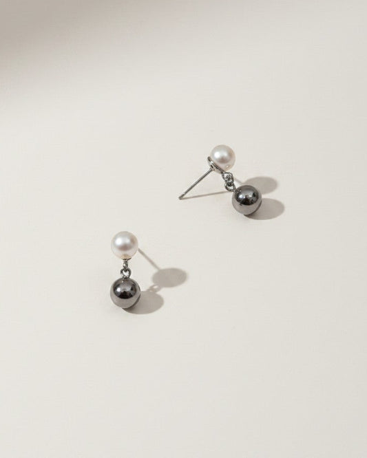 Pair of silver earrings with pearls on a light gray background