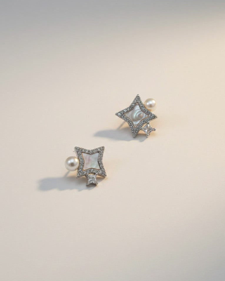 Pair of square-shaped earrings with pearls on a light gray background