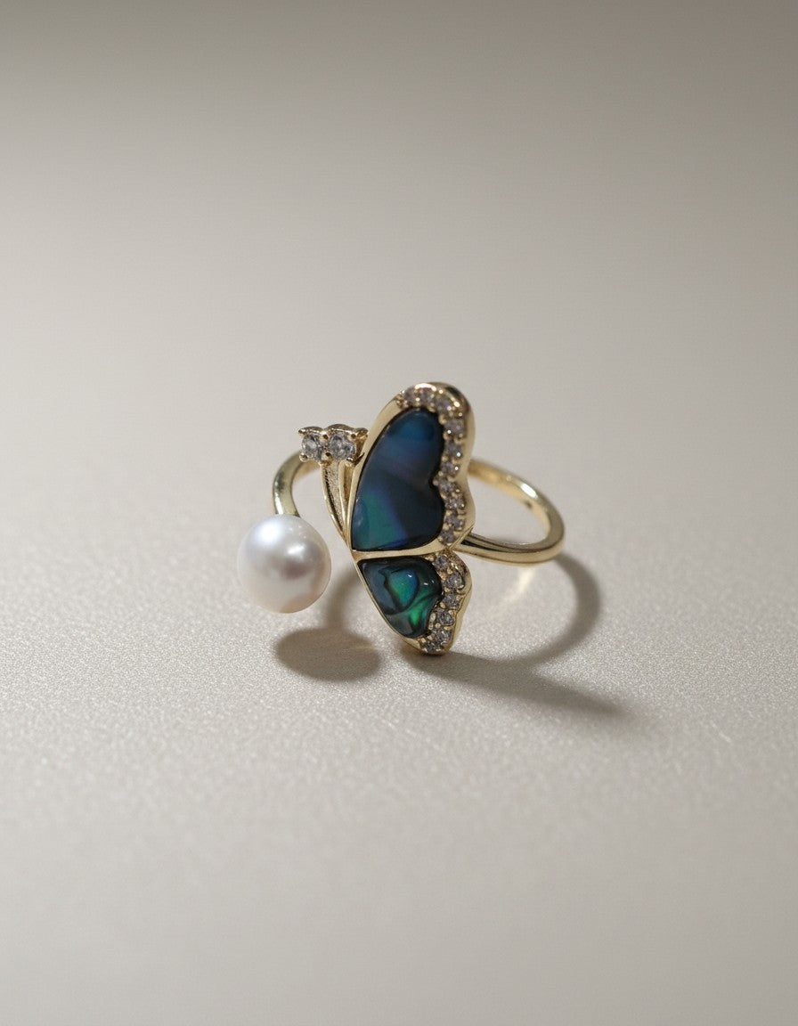 Muchi Butterfly ring with abalone inlay, pearl, and cubic zirconia accents. Adjustable gold-tone band.