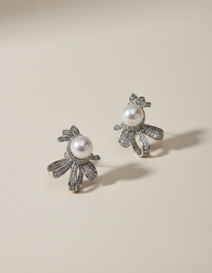 MuchiPearl and crystal bow stud earrings with sterling silver, cubic zirconia, and pearl center. Elegant and whimsical design.