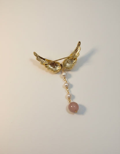Muchic Angel wing brooch with pearls and rose quartz pendant. Gold-tone wings adorned with cubic zirconia, dangling pearls and rose quartz.