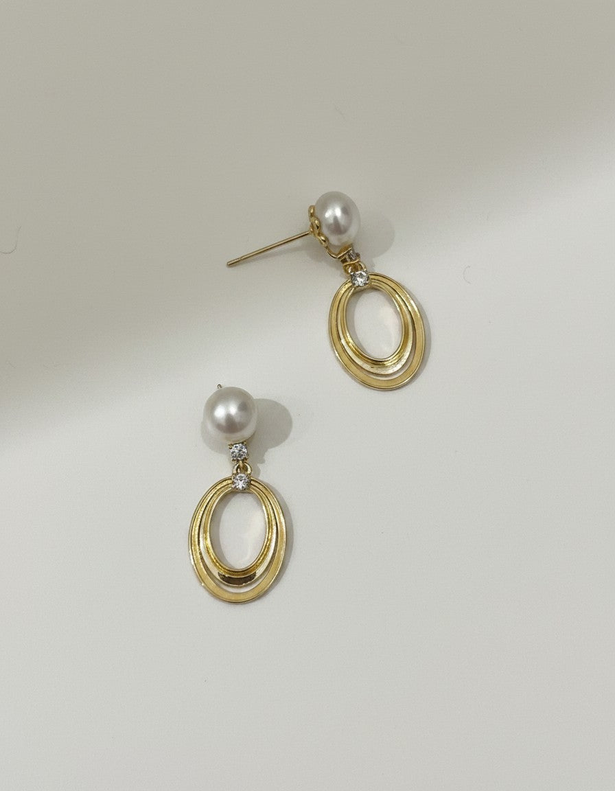 Muchic 14k yellow gold oval pearl drop earrings with diamond accents. Classic pearl suspended above double oval frame.