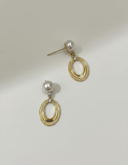 Muchic 14k yellow gold oval pearl drop earrings with diamond accents. Classic pearl suspended above double oval frame.