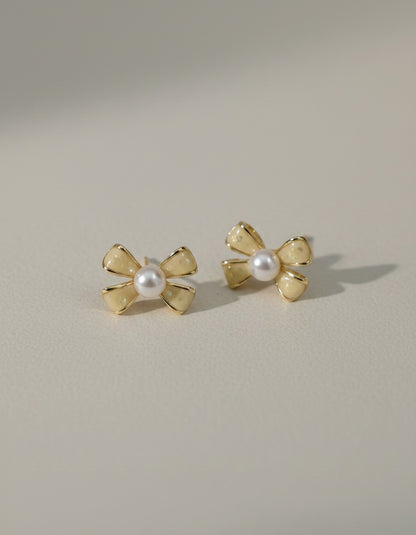 Muchichere bow-shaped stud earrings with faux pearls and creamy yellow enamel. Gold-tone metal.