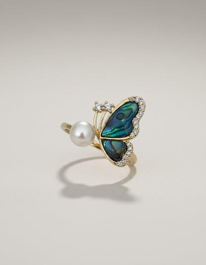 Muchie Butterfly ring with abalone inlay, pearl, and cubic zirconia stones. Adjustable gold-tone band.