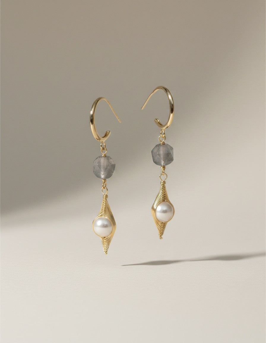 Muchier gold hoop earrings with pearl and grey gemstone accents, featuring a pearl in a wire cage and a faceted grey stone.