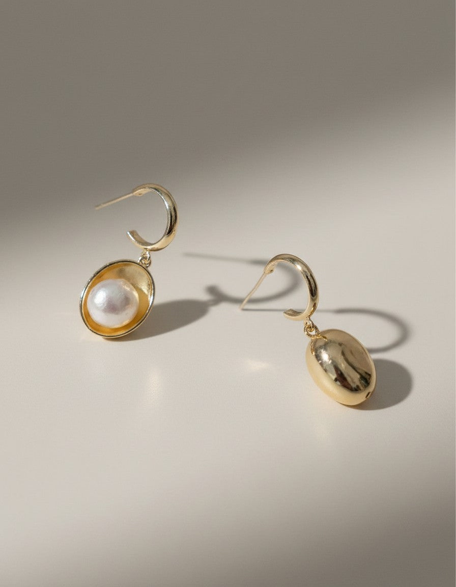 Muchier gold tone oval hoop earrings with pearl accent. Polished gold frame with a lustrous pearl.