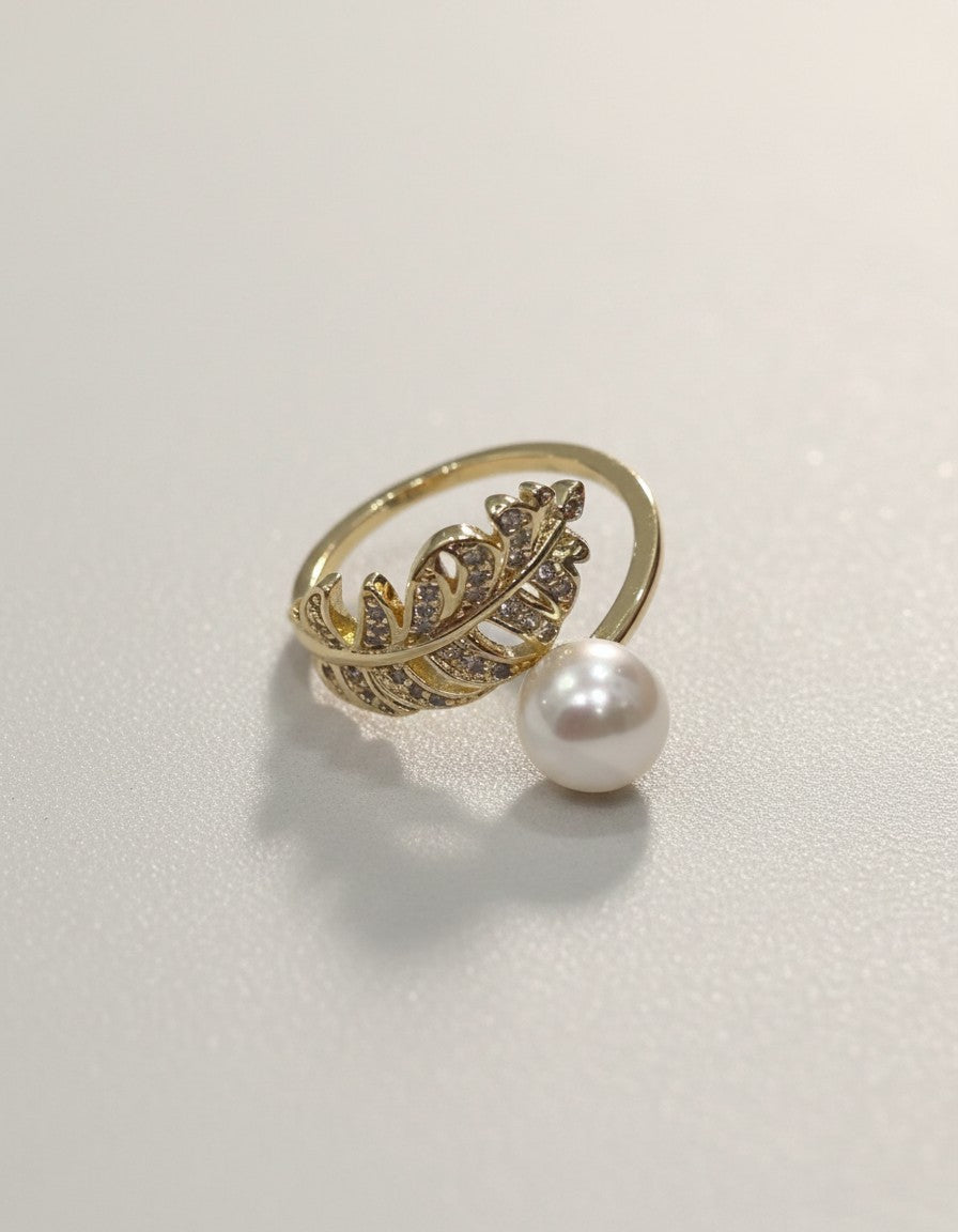 Muchier gold-tone adjustable ring with feather motif and pave cubic zirconia accents, featuring a dangling faux pearl.