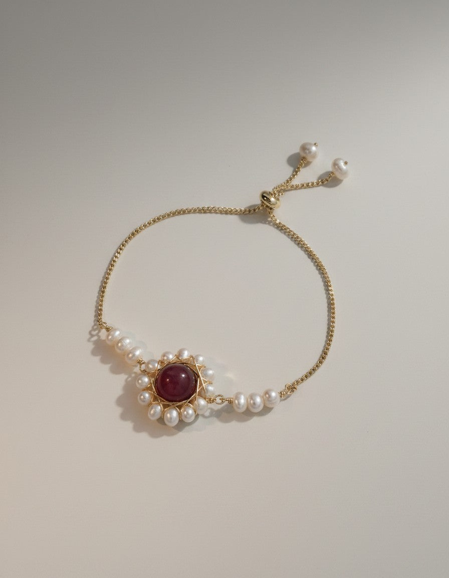 Muchiier adjustable gold-tone bracelet with crimson gemstone center and halo of freshwater pearls.